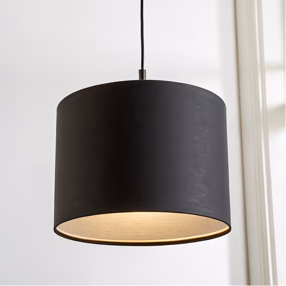 Modern black cylindrical pendant light hanging from a ceiling with soft light glowing from inside.