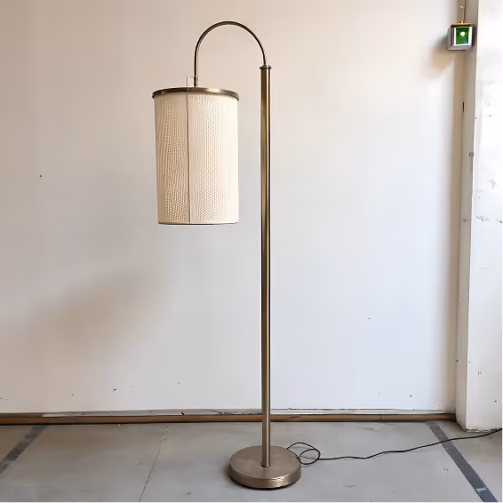 Modern floor lamp with a cylindrical textured beige lampshade and a curved metal stand on a circular base against a plain white wall.