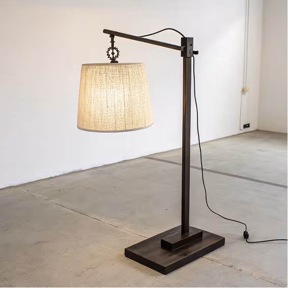Industrial-style floor lamp with a beige textured lampshade and a dark metal frame on a concrete floor.